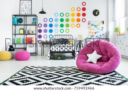 White star pillow on pink pouf in colorful child\'s bedroom with geometric carpet on the floor and stickers on the wall