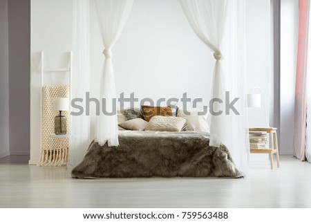Fur brown bedding and glass lamp in minimalist comfy bedroom with natural interior design and bed canopy