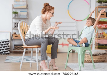 Child psychologist and young kid with ADHD during therapy session in primary school interior