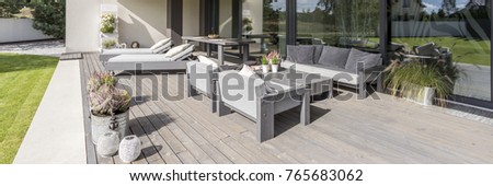 Decorative flowerpots and lanterns on wooden patio on sunny day