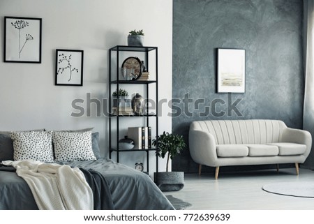 Beige sofa against concrete wall with painting in bedroom with drawings on white wall