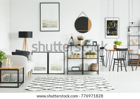 Patterned carpet on the floor and mirror and paintings on the wall in bright living room with sofa between table and lamp