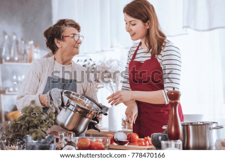 Grandma and granddaughter cooking tomato soup in the kitchen