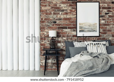 Abstract painting hanging on a brick wall in a flat interior