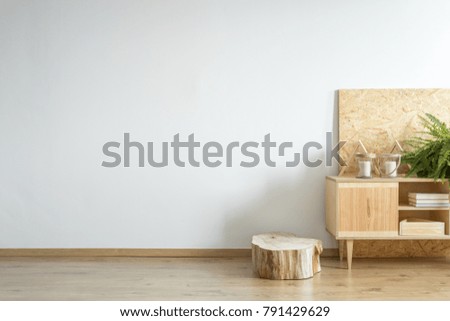 Wooden cupboard standing by a tree trunk in an empty room interior