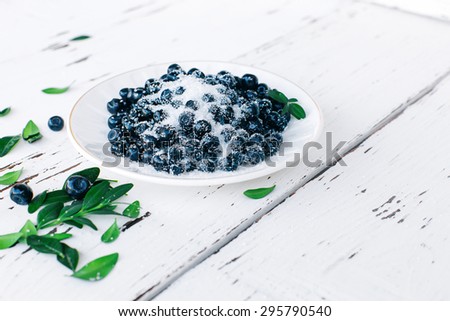Top view of fresh wild berries with sugar on wood background