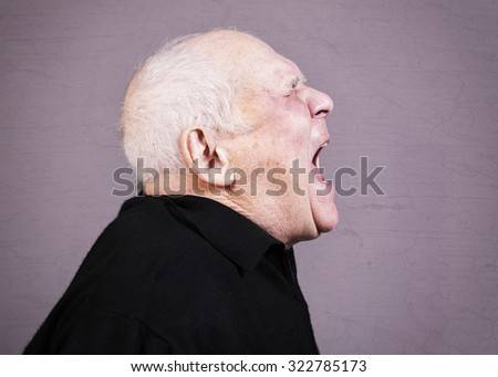 Profile photo of very emotional old man screams  on a gray background.