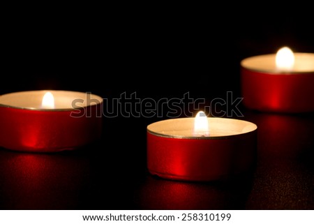 three candles in red candlesticks