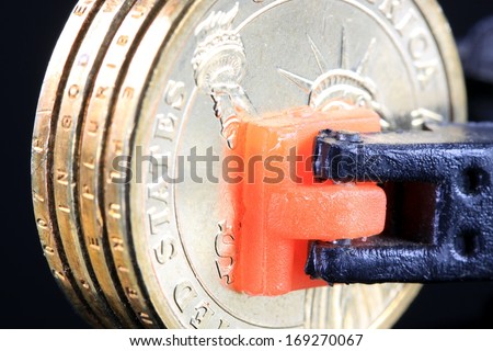 Money is Tight - Financial Concept US Currency gold coins in a tool clamp