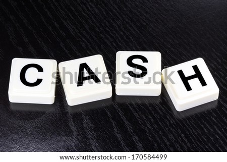 The word cash spelled out with white tiles on black background - A term used for business in finance and stock market trading