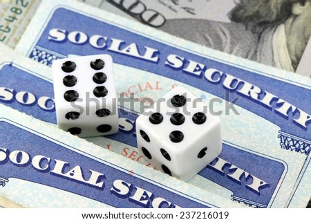 White Dice Laying on Social Security Card - Gambling on benefits and retirement income