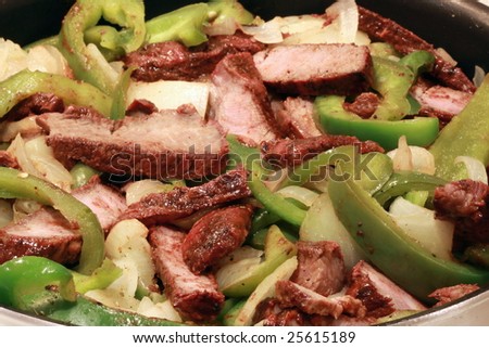 boneless rib meat cooking over onions and peppers for fajitas