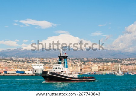 A tug boat leaving the harbor of Catania. Volcano Etna in the background