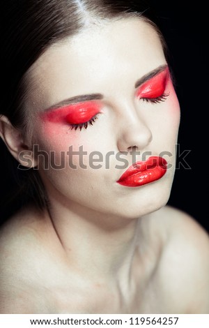 Portrait of a beautiful sexy brunette girl with red lips and red eyes