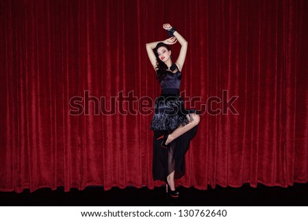 The actress appears on stage in a black dress in front of the scenes
