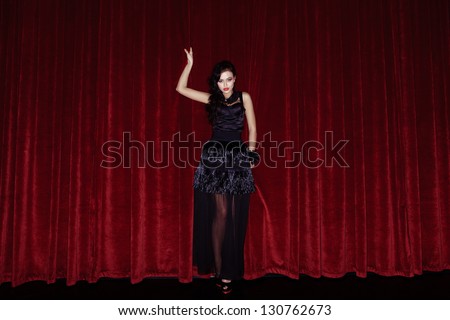 The actress appears on stage in a black dress in front of the scenes