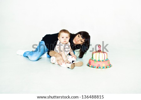 mother and daughter sitting on the floor with cake isolated on white
