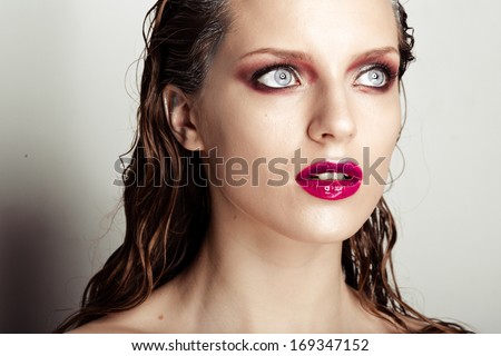 Beautiful girl with a purple lip makeup, clean shiny skin and wet hairstyle, bright eyes. Beauty fashion portrait of a woman face.