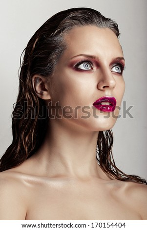 Beautiful girl with a purple lip makeup, clean shiny skin and wet hairstyle, bright eyes. Beauty fashion portrait of a woman face.