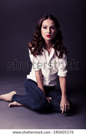 Lovely woman in white blouse and blue jeans pointing