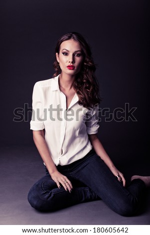 Lovely woman in white blouse and blue jeans pointing