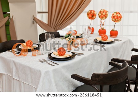 Table set for 4 people. Orange decor and flowers