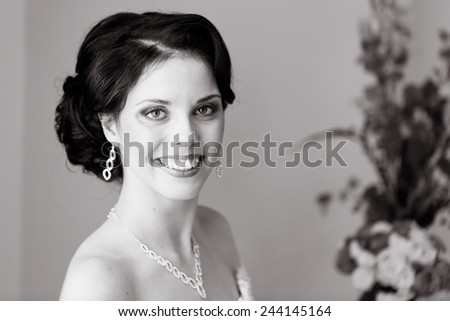 Gorgeous bride in wedding dress in luxury interior with diamond jewelry posing at home and waiting for groom. Romantic rich happy girl in bridal dress smiling have final preparation for wedding