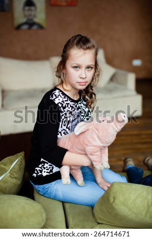 Girl sitting on the couch with a pig on his hands