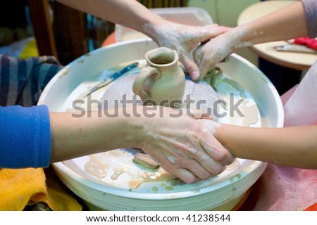 Adult and child cut off the bottom of a clay cup