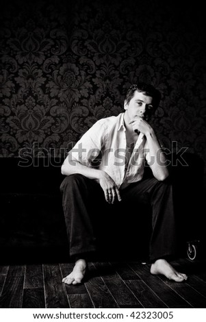 The man thinks barefoot sitting on a sofa