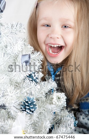 blonde girl in a sweater laughs next to a white Christmas tree