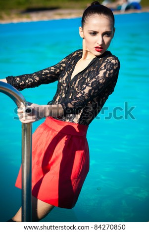 Fashion woman posing poolside in red skirt