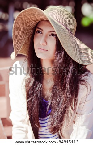 Photo of a young beautiful woman brunette fashion fabrics in today's casual elegant hat with a bag