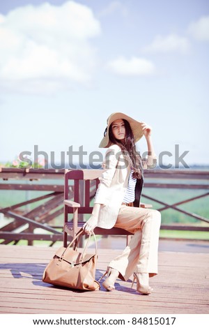 Photo of a young beautiful woman brunette fashion fabrics in today\'s casual elegant hat with a bag