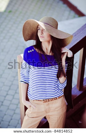 Photo of a young beautiful woman brunette fashion fabrics in today\'s casual elegant hat with a bag