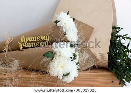 Two bouquets of white chrysanthemums in a paper cornet. \