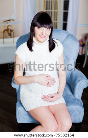 Pregnant woman in a sweater and socks sitting in a armchair