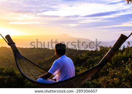 Portrait of a man sitting on a wooden cribs watching the sunrise