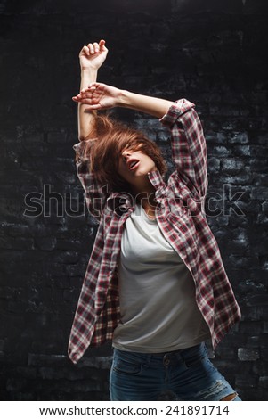 Dancing woman in jeans and white t-shirt in the dark room