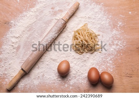 rolling pin, pasta, eggs and flour on the wooden board