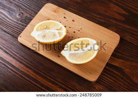 Lemon halves with spices, lying on wooden board on wooden table
