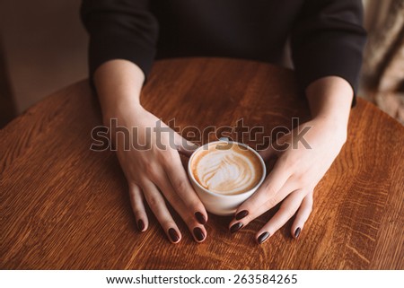 Woman hands holding mug of hot drink that standing on wooden table