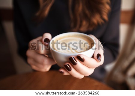 Woman hands holding mug of hot drink that standing on wooden table