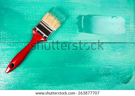 Varnishing a wooden shelf using paintbrush, turquoise color