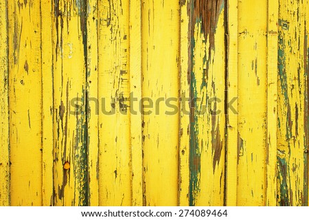 Background of yellow, peeling paint on an old wooden wall