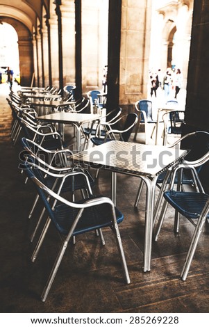 Street cafe in Barcelona with square metal table and wicker chairs on the background of blurred street with people