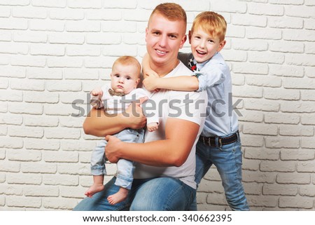 Happy dad hugging his two sons on the background of brick wall