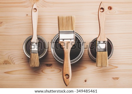 Copy space with three paint brushes on three cans lying on wooden clean table. Top view