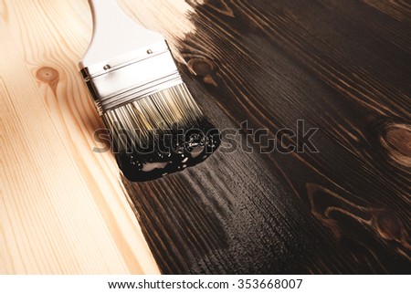 Varnishing natural wood with paint brush in brown color.
