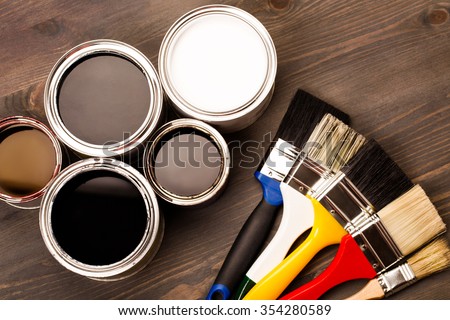 House renovation, paint cans and colored brushes on the wooden grey background